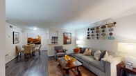 Located at 3000 Greenridge Dr in Houston, Texas, this single-story residence offers a thoughtfully designed layout with warm, neutral tones throughout. The living room serves as the heart of the home, featuring crown molding, dark hardwood-style flooring, and a jute area rug that grounds the comfortable seating arrangement. Warm ambient lighting from floor and table lamps creates an inviting atmosphere, complemented by decorative wall art that adds a distinctive character to the space. An open sightline connects the living area to both the dining room and kitchen, enhancing the sense of flow. The dining area accommodates a round glass-top table with upholstered chairs and features bold, large-scale artwork that adds visual depth. The kitchen is outfitted with white cabinetry, granite-look countertops, a tile backsplash, stainless steel appliances, and durable wood-style flooring. The bedroom offers a calm retreat with plush carpeting, a ceiling fan, natural light from a window with drape treatments, and ample space for a large bed and dresser. The bathroom provides practical functionality with a granite-topped vanity, a tub-shower combination with tile surround, white cabinetry for storage, and a large mirror above the sink.