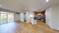 This single-floor residence offers a thoughtfully designed open-concept layout that seamlessly connects the living, dining, and kitchen areas. Warm hardwood-style flooring runs throughout, lending a cohesive and inviting character to every room.

The kitchen is a standout feature, equipped with a full suite of stainless steel appliances including a gas range, microwave, and refrigerator. Rich dark granite countertops contrast beautifully with the warm-toned wood cabinetry that extends to the ceiling, maximizing storage. A peninsula with bar seating bridges the kitchen and living area, ideal for casual dining or entertaining.

The living and dining areas are generously proportioned, filled with natural light from large sliding glass doors that open to a balcony overlooking lush greenery. A pendant light fixture adds a refined touch to the dining space.

The bedrooms are well-sized, each featuring hardwood-style floors, ceiling fans, and windows that invite natural light. One bedroom includes direct access to an outdoor space, enhancing the sense of openness.

The bathrooms are finished with light tile flooring and clean, neutral tones. One features a walk-in glass-enclosed shower with tile surround, while the other includes a dark granite vanity top with white cabinetry, maintaining a consistent design palette throughout the home.