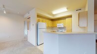 This single-floor residence offers a functional and comfortable layout with a neutral color palette throughout. The kitchen is equipped with light wood cabinetry, white appliances including an electric range, built-in microwave, and refrigerator, complemented by light countertops and a peninsula that opens toward the living area. The kitchen transitions seamlessly into a generously sized living space featuring plush wall-to-wall carpeting, baseboard heating, and multiple windows that invite ample natural light and outdoor views.

The bedrooms are carpeted and feature baseboard heating, window blinds, and sliding closet doors providing practical storage. One bedroom includes access to a dedicated walk-in closet with built-in shelving. A vanity area with cabinetry adjacent to the walk-in closet adds additional convenience.

The two full bathrooms are finished with tile flooring, white vanities with mirrored medicine cabinets, and bathtub/shower combinations fitted with sliding glass enclosures and chrome fixtures. The overall ambiance of the space is clean, bright, and understated, with consistent neutral tones creating a calm and move-in-ready environment throughout.