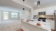 Located in Lewis Center, Ohio, this well-appointed two-story home offers three bedrooms and three bathrooms across two thoughtfully laid-out floors. The main level features warm hardwood-style flooring throughout the kitchen and entry areas, transitioning to plush carpet in the living room. The open-concept kitchen is a standout, showcasing white shaker cabinetry, striking granite countertops, a large island with an undermount sink and pendant lighting, and a full suite of stainless steel appliances. The adjacent living room is bright and welcoming, with neutral tones, crown molding, and large windows that invite natural light. An entrance, hallway, garage access, and patio round out the ground floor. Upstairs, the generously sized primary bedroom includes a walk-in closet with built-in shelving and a private en-suite bathroom featuring a dual-sink granite vanity and a glass-enclosed walk-in shower with hardwood-style flooring. Two additional bedrooms, each with ample closet space, share access to the remaining bathrooms. A dedicated laundry room on the upper level includes a full-size washer and dryer with utility sink. With seven closets and abundant storage throughout, this home is as functional as it is comfortable, set within a well-maintained neighborhood community.
