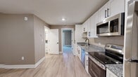Located at 1551 Johnson Ferry Rd in Marietta, GA, this 2-bedroom, 2-bathroom single-floor residence offers a thoughtfully designed layout with modern finishes throughout. The kitchen is a standout feature, outfitted with white shaker-style cabinetry accented by matte black hardware, granite countertops, a stainless steel appliance suite including a refrigerator, range, microwave, and dishwasher, and light wood-look luxury vinyl plank flooring. An open sightline connects the kitchen to the main living area, creating an efficient and functional flow. Both bedrooms are carpeted and filled with natural light from large windows with views of surrounding greenery. The primary bedroom is generously sized and includes a dedicated closet, while the second bedroom also features a closet and its own window. Each bathroom is finished consistently with granite-top white vanities, matte black fixtures, and tile-look flooring, with one bathroom featuring a walk-in shower with built-in shelving and a barn-style door. A stacked washer and dryer unit is conveniently tucked within the unit. Warm taupe wall tones and white trim are carried throughout, lending the space a cohesive, clean aesthetic.