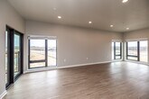 This single-floor unit showcases a thoughtfully designed, contemporary layout with a clean, neutral palette throughout. The spacious open-concept living area is a standout feature, with light wood-style flooring, recessed lighting, and an abundance of natural light streaming through multiple large black-framed windows. A sliding glass door leads to a private balcony, offering open views of the surrounding landscape.

The kitchen is efficiently laid out with white shaker-style cabinetry featuring black hardware, stone-look countertops, a stainless steel sink, and a full suite of stainless steel GE appliances, including a French door refrigerator, range, over-the-range microwave, and dishwasher.

The bedrooms are carpeted for comfort and each includes a ceiling fan and large window with outdoor views. The primary bathroom is notably spacious, featuring dual vanities on opposing walls with white cabinetry and quartz countertops, wood-style flooring, and a separate water closet. A second bathroom offers a long double-sink vanity with matching finishes.

A dedicated laundry room houses a full-size front-loading GE washer and dryer with built-in wire shelving above, completing this well-appointed unit.