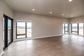 This single-floor unit showcases a thoughtfully designed, contemporary layout with a clean, neutral palette throughout. The spacious open-concept living area is a standout feature, with light wood-style flooring, recessed lighting, and an abundance of natural light streaming through multiple large black-framed windows. A sliding glass door leads to a private balcony, offering open views of the surrounding landscape.

The kitchen is efficiently laid out with white shaker-style cabinetry featuring black hardware, stone-look countertops, a stainless steel sink, and a full suite of stainless steel GE appliances, including a French door refrigerator, range, over-the-range microwave, and dishwasher.

The bedrooms are carpeted for comfort and each includes a ceiling fan and large window with outdoor views. The primary bathroom is notably spacious, featuring dual vanities on opposing walls with white cabinetry and quartz countertops, wood-style flooring, and a separate water closet. A second bathroom offers a long double-sink vanity with matching finishes.

A dedicated laundry room houses a full-size front-loading GE washer and dryer with built-in wire shelving above, completing this well-appointed unit.