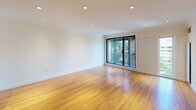 Located at 1443 Beacon St in Brookline, MA, this single-floor residence offers a thoughtfully designed open-concept layout finished with warm hardwood flooring and crown molding throughout. Recessed lighting illuminates the generously sized living area, which flows seamlessly toward a large sliding glass door that opens to an outdoor space, inviting natural light and views of the surrounding urban landscape.

The kitchen is a standout feature, showcasing rich cherry wood cabinetry, striking dark granite countertops, and a large peninsula that provides both additional workspace and a natural divider between the kitchen and living areas. Stainless steel appliances, including a French door refrigerator, built-in microwave, and a double oven range, complete the well-equipped space. Under-cabinet lighting adds a polished finishing touch.

The bedroom features broad windows framing views of the Brookline skyline and treetops, with the same warm hardwood flooring and crown molding continuing throughout. The bathroom is cleanly designed with light travertine-style tile flooring, a glass-enclosed tub and shower combination, a white vanity with ample storage, and crisp white walls that enhance the sense of brightness and space.
