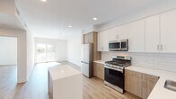 Located at 505 Silver Lake Blvd in one of Los Angeles' most vibrant neighborhoods, this modern single-floor unit offers a clean, contemporary design throughout. Light-toned hardwood flooring flows seamlessly across the open-concept living and kitchen areas, enhancing the bright, airy ambiance created by recessed lighting and large windows that invite natural light.

The kitchen is a standout feature, designed with a two-tone cabinetry scheme pairing white upper cabinets with warm wood-finish lower cabinets. A classic white subway tile backsplash complements the crisp white countertops, while a full suite of stainless steel appliances — including a side-by-side refrigerator, gas range, built-in microwave, and dishwasher — provides both style and function.

The living area is open and versatile, with a sliding glass door leading to an outdoor space and a window framing views of the surrounding Silver Lake neighborhood. The bedroom is a calm, minimalist retreat with a window overlooking the outdoors.

Two bathrooms serve the unit, one featuring a tiled tub-shower combination with grab bars, and the other a streamlined half-bath with a white vanity and large mirror. A dedicated in-unit laundry closet houses a stacked Samsung washer and dryer, adding everyday convenience to this thoughtfully designed Silver Lake residence.