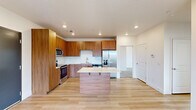 This well-designed 2-bedroom, 2-bathroom residence offers a thoughtfully laid-out single floor with a clean, contemporary aesthetic throughout. The open-concept kitchen and living area serves as the heart of the home, featuring warm wood-toned cabinetry that extends to the ceiling, light quartz countertops, a white subway tile backsplash, and a full suite of stainless steel appliances including a refrigerator with ice maker, range, microwave, and dishwasher. A central kitchen island provides additional prep space and casual seating. Light-toned hardwood flooring flows through the main living areas, adding warmth and continuity. The spacious primary bedroom is a standout, offering dual corner windows that flood the room with natural light and frame views of the surrounding landscape, complemented by plush carpeting and a ceiling fan. The second bedroom is equally comfortable, with its own window, ceiling fan, and access to a private balcony through a glass door. Each bathroom is finished in a crisp, clean style — one featuring a full soaking tub and shower combo with built-in shelving, the other a glass-enclosed walk-in shower. The overall ambiance is bright, modern, and move-in ready.