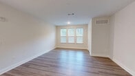 Located at 4705 Windsong Dr in Virginia Beach, VA, this single-floor residence offers a clean, modern aesthetic with quality finishes throughout. The open-concept kitchen and living area form the heart of the home, anchored by light wood-look luxury vinyl plank flooring that flows seamlessly through the main spaces. The kitchen is a standout feature, boasting white shaker-style cabinetry, quartz countertops, a subway tile backsplash, a central island, and a full suite of stainless steel appliances including a refrigerator, range, and over-the-range microwave. The living area is bright and open, with large windows that invite natural light and offer views of surrounding greenery. The bedroom is a comfortable retreat finished with plush neutral carpeting, a dedicated closet, and a transom window that adds additional light. Direct access leads to the full bathroom, which features dual sinks, white cabinetry, quartz countertops, a large vanity mirror with modern lighting, and a bathtub with tiled surround. Neutral warm-beige walls and crisp white trim carry throughout, creating a cohesive and inviting atmosphere well-suited for comfortable everyday living.