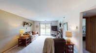 This single-floor residence offers a thoughtfully designed layout that balances comfort and functionality across its key living spaces. The living room is spacious and bright, featuring plush carpeting, neutral walls, and a large sliding glass door that fills the room with natural light and provides views of the surrounding greenery outdoors. A ceiling fan-lit dining area sits adjacent, offering a welcoming space for meals with warm-toned carpet and easy access to the rest of the home.

The kitchen is well-equipped with a generous run of oak cabinetry, ample countertop workspace, a stainless steel electric range, and black appliances including a full-size refrigerator and dishwasher, all set on easy-to-maintain tile flooring. A bedroom area offers carpeted comfort and includes a sliding closet for organized storage. The primary suite features a private ensuite bathroom with a long vanity, extended countertop, and a walk-in closet with built-in shelving. A second full bathroom includes a tub-shower combination, vanity with storage, and overhead cabinetry. Throughout the home, wood-trimmed doors, neutral tones, and consistent finishes create a cohesive and inviting atmosphere.