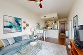Located in the heart of downtown Orlando, this one-bedroom, one-bathroom high-rise residence offers a thoughtfully designed open-concept layout with stunning panoramic city views. The combined living, dining, and kitchen area serves as the centerpiece of the home, featuring rich hardwood flooring, soaring ceilings, and dramatic floor-to-ceiling windows that flood the space with natural light and frame breathtaking views of the Orlando skyline. A ceiling fan adds a practical touch to the airy living area.

The kitchen is equipped with stainless steel appliances, white cabinetry, dark countertops, and stylish pendant lighting above a breakfast bar — ideal for both cooking and casual dining. The entrance hallway, finished with tile flooring, leads conveniently to an in-unit laundry area and multiple closets, including a spacious walk-in closet with built-in shelving and hanging rods.

The bedroom is a serene retreat, accented by a sage green feature wall, plush carpeting, and large windows offering abundant natural light and city views. The bathroom features a dark granite vanity, tile flooring, and clean, modern finishes. A private balcony completes the residence, providing an outdoor space to enjoy the vibrant Orlando cityscape.