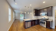 Located at 2775 Stowmarket Ave in Rockford, IL, this single-story home offers a well-designed layout across two bedrooms, two bathrooms, a combined kitchen and living room, a garage, a utility room, and two closets. The living room is bright and spacious, featuring warm hardwood flooring, a ceiling fan, recessed lighting, and a sliding glass door that opens to a wooden deck overlooking a lush, tree-lined backyard — ideal for outdoor relaxation. The kitchen is equipped with rich dark cabinetry, granite countertops, hardwood floors, and stainless steel appliances, creating a functional and stylish cooking space. The primary bedroom is generously sized with plush carpeting, a ceiling fan, and direct access to an en-suite bathroom. The second bedroom also features carpet and a ceiling fan, with ample natural light from a window. Both bathrooms are finished with dark wood vanities and granite countertops; the full bath includes a tub-shower combination and hardwood flooring. Closets are outfitted with wire shelving systems for organized storage. The attached garage is spacious with a concrete floor and automatic opener. The exterior showcases vinyl siding, a back deck, and a sloped green yard bordered by mature trees, offering a peaceful natural setting.