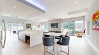 Located at 200 Eastwick Dr in Reading, PA, this single-floor amenity facility offers a thoughtfully designed layout encompassing a generous total floor area. The space combines modern aesthetics with functional design throughout its key areas.

The combined kitchen and living room serves as a central social hub, featuring a sleek, contemporary kitchen with wood-toned cabinetry, stainless steel appliances, a large white island with bar seating, and pendant lighting beneath a recessed ceiling detail. The adjacent lounge area opens via floor-to-ceiling sliding glass doors to an outdoor pool and patio, flooding the space with natural light and offering seamless indoor-outdoor connectivity. Vibrant artwork adds a lively, welcoming character to the room.

The exercise room is well-appointed with a wide array of cardio and strength equipment, including treadmills, ellipticals, stationary bikes, cable machines, and free weights. Large windows and glass partitions allow natural light to pour in, with views of the outdoor pool area. Motivational wall graphics and linear LED lighting complete the energetic atmosphere.

The office features multiple computer workstations with ergonomic seating and warm strip lighting, providing a quiet, productive environment. The hallway entrance welcomes visitors with large glazed doors, abundant natural light, and contemporary furnishings.