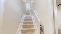 Located at 202 Adams Pointe Blvd N in Mars, PA, this two-story home offers a well-designed layout across two levels. The main living floor features an open-concept kitchen and living room with light wood-look tile flooring and a ceiling fan. The kitchen is a standout, boasting rich dark wood cabinetry with granite countertops, a peninsula with a built-in sink, stainless steel appliances, and recessed lighting. The living area flows naturally from the kitchen, separated by a half-wall partition that adds architectural interest without closing off the space.

The primary bedroom is generously sized with plush carpeting, a ceiling fan, and a window that brings in natural light. A dedicated closet and hallway connect the bedroom to the full bathroom, which features a tiled tub-shower combination with sliding glass doors, a mosaic accent tile border, and brushed nickel fixtures.

Additional highlights include a laundry room, a carpeted staircase with a wood handrail leading between floors, and an attached garage with a concrete floor and interior access door. The home presents a clean, neutral palette throughout, making it move-in ready with a fresh, modern aesthetic.