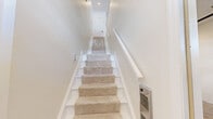 Located at 202 Adams Pointe Blvd N in Mars, PA, this two-story home offers a well-designed layout across two levels. The main living floor features an open-concept kitchen and living room with light wood-look tile flooring and a ceiling fan. The kitchen is a standout, boasting rich dark wood cabinetry with granite countertops, a peninsula with a built-in sink, stainless steel appliances, and recessed lighting. The living area flows naturally from the kitchen, separated by a half-wall partition that adds architectural interest without closing off the space.

The primary bedroom is generously sized with plush carpeting, a ceiling fan, and a window that brings in natural light. A dedicated closet and hallway connect the bedroom to the full bathroom, which features a tiled tub-shower combination with sliding glass doors, a mosaic accent tile border, and brushed nickel fixtures.

Additional highlights include a laundry room, a carpeted staircase with a wood handrail leading between floors, and an attached garage with a concrete floor and interior access door. The home presents a clean, neutral palette throughout, making it move-in ready with a fresh, modern aesthetic.