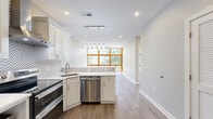 Located at 3555 Georgia Ave NW in Washington, DC, this thoughtfully designed one-bedroom, one-bathroom residence offers a bright and modern living experience across a single floor. The open-concept kitchen and living area serves as the heart of the home, anchored by a dramatic wall of wood-framed, floor-to-ceiling windows that flood the space with natural light and frame lush tree-lined views of the neighborhood. Light-toned hardwood flooring and soft gray walls create a clean, contemporary aesthetic throughout.

The kitchen is well-appointed with white shaker cabinetry, sleek quartz countertops, a geometric herringbone tile backsplash, and a full suite of stainless steel appliances including a French door refrigerator, electric range, built-in microwave, and dishwasher. A pendant light fixture above the peninsula adds a stylish focal point.

The bedroom is a comfortable, well-lit retreat, benefiting from its own large wood-framed windows with treetop and street views, and the same warm hardwood flooring found throughout the unit.

The bathroom is a standout feature, showcasing floor-to-ceiling marble-look porcelain tile in the walk-in shower, complete with a rainfall showerhead, handheld fixture, and a recessed niche. White cabinetry and bright finishes complete the refined look.