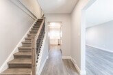 Located at 863 Warwick Dr in Burlington, Ontario, this three-storey home offers a thoughtfully organized layout across three distinct levels. The main floor welcomes visitors with an open entryway featuring a wood-and-metal staircase with clean white risers, leading the eye toward a bright, modern kitchen. The kitchen is outfitted with crisp white cabinetry, white quartz countertops, stainless steel appliances including a refrigerator, range, microwave, and dishwasher, as well as a double undermount sink beneath a natural light-admitting window. Light wood-tone luxury vinyl flooring flows consistently throughout all levels, complementing the soft grey and white wall tones. The upper floors house multiple well-proportioned rooms, each featuring windows that invite natural light and offer views of the surrounding greenery. The bathrooms are finished in a clean, modern style with white tile, a soaker tub-shower combination, and sleek white vanities. A lower level provides additional usable space. Recessed lighting on the main floor and flush-mount fixtures on upper levels maintain a cohesive, contemporary aesthetic throughout this move-in-ready Burlington home.