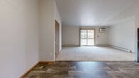 Located at 540 McKinley Ave in Clintonville, Wisconsin, this two-bedroom, one-bathroom unit offers a practical and comfortable single-floor layout. The open-concept kitchen and living room form the heart of the space, with wood-look plank flooring throughout the kitchen area transitioning to plush carpet in the living room. The kitchen is equipped with warm oak cabinetry, light countertops, and a full suite of black appliances including a refrigerator, dishwasher, gas range, and microwave. A sliding glass door in the living area opens to a private balcony, allowing natural light to fill the room. A wall-mounted A/C unit and baseboard heating provide year-round climate control. Both bedrooms feature soft carpeting, ceiling fans, and ample natural light from windows with views of the surrounding area. The primary bedroom includes access to a spacious walk-in closet with built-in shelving and hanging rods for generous storage. An additional bedroom features a bifold closet. The full bathroom offers a single-sink vanity with oak cabinetry, a tub-shower combo, and wood-look flooring consistent with the rest of the unit. A dedicated closet rounds out the storage options in this well-organized and move-in ready space.