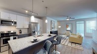 Located at 2312 Bristol Creek Dr in Morrisville, NC, this single-story residence offers a thoughtfully designed open-concept layout with contemporary finishes throughout. The kitchen is a standout feature, showcasing granite countertops, a two-toned cabinet scheme with white upper cabinets and dark lower cabinets, a classic subway tile backsplash, stainless steel appliances, and a large island with seating — ideal for casual dining and entertaining. Pendant and track lighting illuminate the space with a modern touch. The kitchen flows seamlessly into the living and dining areas, which are finished with durable wood-look flooring and ceiling fans. The living area offers a comfortable, open atmosphere with ample room for relaxing or hosting guests. The bedrooms are carpeted for warmth and comfort, each equipped with ceiling fans and windows that allow natural light to fill the rooms. The primary bedroom features a walk-in closet with wire shelving for organized storage. The bathroom is outfitted with granite countertops, a dark-toned vanity with modern hardware, and wood-look flooring that carries a consistent design aesthetic throughout the home. Clean lines, neutral tones, and quality finishes define the overall ambiance of this well-appointed residence.
