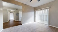 This single-floor residence offers a straightforward and functional layout designed for comfortable everyday living. The living area is finished with plush carpeting and features a ceiling fan overhead, while a large sliding glass door fitted with vertical blinds fills the space with natural light and provides outdoor access. The open sightlines connect the living area to the rest of the home, creating a cohesive and airy feel throughout.

The galley-style kitchen is efficiently laid out with white cabinetry, granite-look countertops, and wood-look flooring. White appliances — including a full-size refrigerator, electric range, and over-the-range microwave — are all included. A window at the end of the kitchen brings in additional natural light.

The bedroom is generously sized, carpeted, and fitted with a ceiling fan. A wall of mirrored sliding closet doors adds depth to the room while providing ample storage. Natural light filters in through a window with blinds.

The bathroom features wood-look flooring, a white vanity with a granite-look countertop, a large mirror, and an over-toilet cabinet for added storage. The neutral gray and white tones throughout the home create a clean, cohesive aesthetic. The entry area connects the spaces with durable wood-look flooring and provides a welcoming transition into the home.