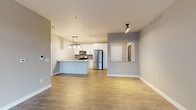 Located at 637 W Main Stone in Sun Prairie, Wisconsin, this single-floor residence offers a thoughtfully designed, contemporary living space with a clean, modern aesthetic throughout. The open-concept layout seamlessly connects the living area to the kitchen, creating a spacious and functional flow. Light wood-look flooring anchors the main living and kitchen areas, while neutral gray walls provide a versatile backdrop.

The kitchen is a standout feature, equipped with stainless steel appliances including a French door refrigerator, gas range, and microwave. Crisp white cabinetry extends to the ceiling, maximizing storage, while a peninsula with granite countertops and pendant lighting serves as both a prep space and casual dining area. A subway tile backsplash adds a polished finishing touch.

The bedroom offers plush carpeting and direct access to a generously sized walk-in closet with built-in shelving. The full bathroom features granite countertops, an undermount sink, a backlit vanity mirror, and a combination tub and shower. A dedicated laundry area includes a full-size washer and dryer with overhead shelving for added storage. Track lighting and recessed fixtures illuminate the space throughout, contributing to its bright, well-appointed character.