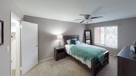 This single-floor residence offers a well-organized layout designed for comfortable everyday living. The open living and dining area serves as the heart of the home, featuring soft carpet underfoot, neutral taupe walls, and a large sliding glass door fitted with vertical blinds that allows natural light to fill the space. The dining area transitions seamlessly from the living room, with hardwood-style flooring providing a distinct visual separation between the two zones.

The kitchen is efficiently designed with white cabinetry, dark countertops, a stainless steel sink, and a full suite of appliances including a refrigerator and dishwasher. Under-cabinet lighting adds warmth to the functional workspace, while durable hardwood-style flooring continues throughout.

The primary bedroom is generously proportioned, featuring plush carpet, a ceiling fan with light fixture, and a window that allows natural light in. A second bedroom offers similar finishes with ceiling fan lighting and carpeted floors, making it well-suited as a children's room or guest space.

The bathroom features classic tile wainscoting in warm tones, a tub-shower combination, and practical fixtures. Throughout the residence, the consistent neutral color palette and practical finishes create a cohesive, comfortable ambiance.