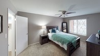 This single-floor residence offers a well-organized layout designed for comfortable everyday living. The open living and dining area serves as the heart of the home, featuring soft carpet underfoot, neutral taupe walls, and a large sliding glass door fitted with vertical blinds that allows natural light to fill the space. The dining area transitions seamlessly from the living room, with hardwood-style flooring providing a distinct visual separation between the two zones.

The kitchen is efficiently designed with white cabinetry, dark countertops, a stainless steel sink, and a full suite of appliances including a refrigerator and dishwasher. Under-cabinet lighting adds warmth to the functional workspace, while durable hardwood-style flooring continues throughout.

The primary bedroom is generously proportioned, featuring plush carpet, a ceiling fan with light fixture, and a window that allows natural light in. A second bedroom offers similar finishes with ceiling fan lighting and carpeted floors, making it well-suited as a children's room or guest space.

The bathroom features classic tile wainscoting in warm tones, a tub-shower combination, and practical fixtures. Throughout the residence, the consistent neutral color palette and practical finishes create a cohesive, comfortable ambiance.