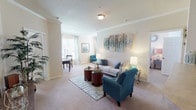 This thoughtfully designed single-floor residence offers a comfortable and cohesive living experience across its well-proportioned rooms. The open-concept living area is bright and welcoming, with warm neutral carpeting, crown molding, and natural light filtering through large windows dressed with sheer curtains. The space flows naturally into a dedicated dining area, which features elegant wall art and plush upholstered seating — ideal for both casual meals and entertaining.

The kitchen is fitted with rich dark wood cabinetry, ample counter space arranged in a U-shaped layout, tile flooring, and black appliances, offering both functionality and a classic aesthetic. Storage is plentiful, with full-height upper cabinets extending across the walls.

The bedroom is generously sized, featuring soft carpeting, a ceiling fan, and windows that allow for natural light. Decorative mirrors above the bed add a stylish focal point, and a walk-in closet provides excellent storage. The adjacent bathroom includes a single vanity with a wide mirror, tile flooring, and a clean, functional layout.

Completing the home is a dedicated in-unit laundry room with a full-size washer and dryer, tile flooring, and overhead shelving for added convenience. Overall, this residence combines practical design with a warm, inviting ambiance throughout.