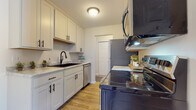 This single-story unit at H2 Flats in Mounds View, Minnesota offers a thoughtfully designed layout that balances functionality and modern style. The living area is open and welcoming, featuring wood-look plank flooring, neutral walls, and a large window that allows generous natural light to fill the space, creating a bright and airy atmosphere.

The galley-style kitchen is well-equipped and stylishly updated with white shaker cabinetry, black hardware accents, and light marble-patterned countertops. A black undermount sink, stainless steel dishwasher, electric range, and over-the-range microwave complete the kitchen, offering ample functionality within an efficient footprint. The wood-look flooring continues seamlessly throughout.

The bedroom is a calm retreat with plush carpeting, a ceiling fan, a window with vertical blinds, and a closet with built-in shelving for convenient storage.

The full bathroom features a clean, white aesthetic with a tub-shower combination, a white vanity with storage, and wood-look flooring that ties the space together cohesively.

Throughout the unit, a consistent palette of whites and neutrals creates a fresh, modern ambiance suited for comfortable everyday living.