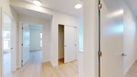 This thoughtfully designed 3-bedroom, 2-bathroom residence offers a clean, contemporary aesthetic across a single floor. Light hardwood flooring flows consistently throughout the space, complementing the crisp white walls and creating a bright, cohesive atmosphere.

The three bedrooms each feature large windows that invite generous natural light and offer outdoor views, including glimpses of the surrounding skyline and greenery. The primary bedroom is a comfortable retreat, while the additional two bedrooms are well-proportioned and versatile. Each bedroom benefits from baseboard heating and efficient use of space, with select rooms including built-in closets with sliding panel doors for streamlined storage.

The two bathrooms are finished in a clean, modern style. One features a full soaking tub with an overhead shower, white tile surround, and light wood flooring. The second bathroom showcases a sleek white vanity with an undermount sink, quartz-style countertop, and a large mirror, adding a refined touch.

A central hallway connects all rooms efficiently, fitted with recessed ceiling lighting that maintains the home's bright, airy feel. The overall design is minimal and modern, making excellent use of the available footprint while delivering a polished, functional living environment.