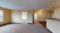 Located at 30 Ferry Street in Middletown, Connecticut, Unit 4D is a well-appointed single-floor residence designed for comfortable everyday living. The open layout connects the living area to the kitchen via a peninsula counter with a dark granite-style surface, creating a functional and cohesive common space. The living area features neutral-toned carpeting and warm yellow walls, lending a bright and welcoming atmosphere throughout.

The galley-style kitchen is outfitted with white cabinetry, dark countertops, and white appliances including a gas range and refrigerator, all set over rich hardwood-style flooring that extends through the kitchen and hallway areas. A pass-through counter connects the kitchen to the main living space, enhancing the open feel.

Two carpeted bedrooms each feature windows with blinds that allow for natural light, along with ample closet space. The bathroom is finished with hardwood-style flooring, a white vanity with a dark countertop, a wall-mounted mirror, and a full tub-shower combination. A separate vanity area adjacent to the bathroom provides added convenience.

Dark baseboards throughout offer a clean contrast to the light-colored walls, contributing to the unit's tidy, consistent aesthetic. The single-floor layout ensures easy accessibility and efficient use of space.