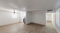This single-floor unit offers a clean, modern aesthetic throughout its well-organized layout. The open living area is finished with light wood-style laminate flooring and crisp white walls, creating a bright and airy atmosphere. A textured popcorn ceiling and ceiling fan add character to the main living space, which receives natural light through windows fitted with vertical blinds and horizontal blinds. The kitchen is thoughtfully updated, featuring white shaker-style cabinetry, a light stone-look countertop, a mosaic tile backsplash, and stainless steel appliances including an electric range with overhead ventilation hood. Bold blue lower cabinetry provides a striking design accent that carries into the bathroom. The bathroom is equipped with a matching blue vanity cabinet topped with a light quartz-style countertop, an undermount sink with brushed nickel fixtures, a framed mirror, and a separate tub-shower combination with white tile surround. The bedroom is generously sized and includes two side-by-side sliding-door closets offering ample storage, complemented by a ceiling fan overhead. The consistent flooring and neutral color palette throughout the unit create a cohesive and functional living environment.