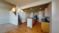 Located at 8150 W 12th St in Greeley, Colorado, this two-story home offers a functional and well-appointed layout across both levels. The main floor centers around an open-concept kitchen, which features light oak cabinetry, dark granite-style countertops, a central island with additional storage and seating space, and black appliances including a refrigerator, range, and built-in microwave. Recessed lighting illuminates the kitchen, complemented by a decorative pendant chandelier that adds warmth to the adjacent dining area. Warm wood-look flooring extends throughout the main level, creating a cohesive and inviting atmosphere. A convenient half bathroom on the main floor includes a single vanity with matching cabinetry and dark countertop. The staircase, finished with carpet treads, leads to the upper level, where the bedrooms are situated. The carpeted bedrooms are bright and generously proportioned, each featuring windows that allow natural light to filter in. A full bathroom upstairs includes a single vanity, tub-shower combination, and tile flooring. A walk-in closet with wire shelving provides ample storage. The home's neutral color palette and practical design make it a versatile and comfortable residence in the Greeley community.