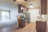 Located at 3572 Banbury Dr in Riverside, California, this single-floor residence offers a practical and well-appointed layout. The kitchen is a standout feature, showcasing rich dark wood cabinetry, granite-style countertops, a double basin sink, stainless steel refrigerator, and a gas range. Wood-look flooring runs through the kitchen and connecting areas, adding warmth and easy maintenance underfoot. A ceiling fan with a light fixture provides both comfort and ambient lighting in the kitchen and adjoining spaces.

The living area transitions from wood-look flooring to plush carpeting, creating a cozy and comfortable atmosphere. A half-wall with a pass-through counter connects the living space to the kitchen, allowing for an open, communicative flow between the two areas.

The bedrooms are carpeted and generously sized, each featuring ample closet space and neutral wall tones that offer a versatile canvas for personalization. The bathrooms are appointed with dark wood vanities, granite-style countertops, well-lit mirrors, and clean white fixtures. Textured ceilings are present throughout the home, and the overall layout is efficient and cohesive, making this a comfortable single-floor living space in a convenient Riverside location.