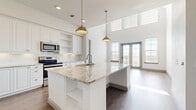 This single-story, 2-bedroom, 3-bathroom home in Plano, Texas offers a thoughtfully designed open-concept layout with modern finishes throughout. The kitchen and living room flow seamlessly together, anchored by a striking oversized island topped with granite countertops and illuminated by stylish brass pendant lights. The kitchen features crisp white shaker cabinetry extending to the ceiling, stainless steel appliances, and a subway tile backsplash. Soaring ceilings and large windows with French doors flood the space with natural light, creating a bright and airy atmosphere. Wood-look flooring runs throughout, adding warmth and continuity. The primary bedroom is a comfortable retreat, accompanied by a spa-inspired ensuite featuring a glass-enclosed walk-in shower with floor-to-ceiling tile work, as well as a spacious walk-in closet with built-in shelving and hanging rods. A second full bathroom includes white cabinetry with granite countertops, a tiled tub-shower combo, and hardwood-style flooring. The second bedroom is well-proportioned, offering a ceiling fan and a large window with natural views. Two closets provide ample storage. The home's clean, neutral palette and quality finishes make it a move-in ready space with lasting appeal.