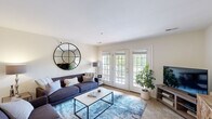 Located at Swan Lake Drive in Charlottesville, Virginia, this two-bedroom, one-bathroom residence offers a thoughtfully designed layout across its main living floor. The spacious living room is a welcoming centerpiece, featuring plush carpeting, neutral walls, and a set of elegant French doors that flood the room with natural light and open onto a private balcony overlooking a serene, tree-lined landscape. A second living area provides additional flexible space for entertaining or relaxing.

The dining area is defined by a charming accent wall, ceiling fan, and soft carpeting, creating an intimate setting for meals. Adjacent to it, the kitchen is efficiently designed with warm wood cabinetry, granite countertops, hardwood-style flooring, and black appliances, with direct access to the in-unit laundry room, which includes a full-size washer and dryer with overhead shelving.

The generously sized primary bedroom features soft blue walls, plush carpeting, and ample closet space, offering a calm and restful retreat. The full bathroom is finished with wood-toned cabinetry, a vanity with a large mirror, and hardwood-style flooring. Two closets throughout the unit provide excellent storage. The private balcony, with its white railing and lush outdoor views, completes this comfortable and well-rounded residence.