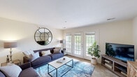 Located at Swan Lake Drive in Charlottesville, Virginia, this two-bedroom, one-bathroom residence offers a thoughtfully designed layout across its main living floor. The spacious living room is a welcoming centerpiece, featuring plush carpeting, neutral walls, and a set of elegant French doors that flood the room with natural light and open onto a private balcony overlooking a serene, tree-lined landscape. A second living area provides additional flexible space for entertaining or relaxing.

The dining area is defined by a charming accent wall, ceiling fan, and soft carpeting, creating an intimate setting for meals. Adjacent to it, the kitchen is efficiently designed with warm wood cabinetry, granite countertops, hardwood-style flooring, and black appliances, with direct access to the in-unit laundry room, which includes a full-size washer and dryer with overhead shelving.

The generously sized primary bedroom features soft blue walls, plush carpeting, and ample closet space, offering a calm and restful retreat. The full bathroom is finished with wood-toned cabinetry, a vanity with a large mirror, and hardwood-style flooring. Two closets throughout the unit provide excellent storage. The private balcony, with its white railing and lush outdoor views, completes this comfortable and well-rounded residence.
