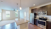 Located at 1612 Burks Mill Ln in Chesapeake, Virginia, this single-floor residence offers a well-designed layout that balances functionality with modern finishes. The open-concept kitchen serves as a central highlight, showcasing rich dark espresso cabinetry that extends to the ceiling for ample storage, granite countertops, a subway tile backsplash, and a full suite of stainless steel appliances including a refrigerator, range, microwave, and dishwasher. A peninsula with a granite overhang provides additional counter space and a natural transition into the living area, which features warm hardwood-style flooring and a ceiling fan with access to natural light through multiple windows overlooking greenery outside.

The bedrooms are carpeted and generously sized, each receiving natural light through large windows with views of surrounding trees. One bedroom connects to a bathroom featuring tile flooring and a soaking tub with tile surround, while another bedroom provides access to a separate bathroom. A spacious walk-in closet with wire shelving offers practical storage. Throughout, the neutral color palette and clean finishes create a bright, move-in-ready atmosphere.