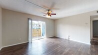 Located at 501 116th Ave N in Saint Petersburg, Florida, this single-floor residence offers a well-organized layout designed for comfortable everyday living. The main living area is finished with durable wood-style flooring that extends throughout the common spaces, lending a clean, cohesive look. A ceiling fan with a light fixture is centrally mounted beneath a textured ceiling, providing both airflow and ambient lighting. Sliding glass doors open to a private outdoor balcony enclosed by a wooden privacy fence, allowing natural light to fill the living space while offering a comfortable outdoor retreat. The kitchen features white cabinetry with ample storage, light countertops, and black appliances, including a full-size refrigerator. It connects seamlessly to the main corridor, which leads to the bedrooms and bathroom. The bedrooms are carpeted, creating a softer, quieter environment, and each room includes windows with blinds for natural light and privacy. Closet access is present in the bedroom area. The bathroom is fitted with wood-style flooring, a white vanity with storage, a tiled tub-shower combination, and clean, simple finishes throughout. Overall, the space presents a practical and functional layout suited to a variety of lifestyles in the heart of the Saint Petersburg area.