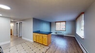 Located at 101 N Grant St in Denver's Capitol Hill neighborhood, this single-floor unit offers a functional and well-organized layout designed for comfortable city living. The kitchen is equipped with black appliances, including a full-size refrigerator, electric range, and microwave, all complemented by light wood cabinetry and tile flooring. A peninsula counter with a dark countertop and additional cabinetry beneath serves as a natural divider between the kitchen and the living area, which features hardwood-style flooring and a large window that fills the space with natural light and views of the surrounding neighborhood. The open layout creates a seamless flow between cooking and living spaces. Two bedrooms are finished with plush carpeting, ceiling fans, and individual wall-unit HVAC systems, each with windows that invite natural light and outdoor views of the tree-lined surroundings. The bathroom is thoughtfully appointed with tile flooring, a wood-trimmed vanity with a dark countertop, and a combination tub and shower equipped with safety grab bars for added accessibility. Throughout the unit, neutral wall tones provide a clean, versatile backdrop, while baseboard heating and wall-unit climate control ensure year-round comfort. The unit's location in Capitol Hill offers convenient access to Denver's vibrant dining, arts, and transit corridors.