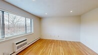 Located at 71 Charlesbank Way in Waltham, Massachusetts, this single-floor, 2-bedroom, 2-bathroom unit offers a functional and well-appointed layout. Warm-toned hardwood flooring extends throughout the main living areas and bedrooms, creating a cohesive and inviting atmosphere. Recessed lighting is featured throughout, complementing the natural light admitted by multiple windows fitted with blinds.

The combined kitchen and living room area forms the heart of the unit. The kitchen is equipped with stainless steel appliances, including a range, built-in microwave, and dishwasher, alongside white cabinetry and granite countertops. Neutral tile flooring grounds the kitchen space.

Both bedrooms are well-proportioned with clean white walls, hardwood floors, and baseboard heating. The primary bedroom offers a generous footprint with ample closet space, including sliding wood-panel closet doors. The second bedroom also provides comfortable space with direct access to the hallway.

Each bathroom features a white vanity with granite countertop, an undermount sink, and a large mirror. One bathroom includes a window with natural light and white tile flooring. Warm wood-panel doors are consistent throughout the unit, adding a classic touch to the overall design.