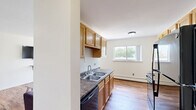 Located at 1815 Deming Dr in Mount Pleasant, Michigan, this single-floor, 2-bedroom, 2-bathroom residence offers a functional and practical layout throughout. The living room serves as a welcoming common area, featuring warm hardwood floors, multiple windows that invite natural light, a wall-mounted air conditioning unit, and baseboard heating. A built-in shelf adds a subtle architectural detail to the space.

The galley-style kitchen is well-equipped with warm-toned wood cabinetry, dark granite-style countertops, a double stainless steel sink, and black appliances including a range, refrigerator, dishwasher, and microwave. Hardwood flooring continues through the kitchen and into the adjoining dining area, which benefits from additional window views of the outdoors.

Both bedrooms are carpeted for comfort and include closet space. The primary bedroom features an open closet alcove and direct access to one of the two full bathrooms. The second bedroom is bright, with windows on two walls providing ample natural light and baseboard heating. Each bathroom includes a tub-shower combination with white tile surround, a toilet, and hardwood-style flooring. Three closets distributed throughout the unit provide generous storage across the floor plan.