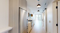 Located at 4135 Park Blvd in San Diego's desirable 92103 neighborhood, this thoughtfully designed single-floor studio maximizes every square foot with a clean, modern aesthetic throughout. Light hardwood flooring flows continuously across the entire space, complementing the bright white walls and creating a cohesive, airy atmosphere.

The galley-style kitchen is well-appointed with stainless steel appliances, including a gas range, built-in microwave, dishwasher, and a full-size refrigerator. Two-tone cabinetry in natural wood and white, paired with a white tile backsplash and a contemporary undermount sink, give the kitchen a refined, modern character. Pendant lighting with matte black dome fixtures illuminates the corridor, adding a stylish accent overhead. A sliding barn door provides convenient access to the in-unit laundry area, which houses a stacked washer and dryer alongside open shelving.

The open living area is filled with natural light, enhanced by a ceiling fan and a full-width sliding glass door that opens onto a private balcony with views of the surrounding San Diego rooftops. The bathroom features a glass-enclosed walk-in shower clad in floor-to-ceiling vertical white tile, brushed nickel fixtures, and classic hexagonal mosaic floor tile, offering a clean and sophisticated finish.