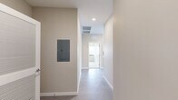 Located on the fifth floor at 500 E 8th Street in Kansas City, Missouri, this 2-bedroom, 2-bathroom unit offers a well-designed layout across a single floor. The open-concept living and kitchen area features polished concrete floors, recessed lighting, and a wall of large, dark-framed floor-to-ceiling windows that flood the space with natural light and frame sweeping views of the Kansas City skyline. The modern kitchen is equipped with stainless steel appliances, including a refrigerator, dishwasher, and range, complemented by light wood cabinetry, white upper cabinets, a subway tile backsplash, and ample counter space. Both bedrooms are carpeted and offer generous proportions, with large windows providing continued city views. The primary bedroom includes a double-door closet for substantial storage. The two bathrooms are finished with vertically stacked white tile; one features a glass-enclosed walk-in shower, while the other offers a full shower-tub combination. A connecting hallway links the private sleeping quarters to the main living area, contributing to a functional and cohesive floor plan. Neutral wall tones throughout lend the space a clean, contemporary aesthetic.