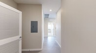 Located on the fifth floor at 500 E 8th Street in Kansas City, Missouri, this 2-bedroom, 2-bathroom unit offers a well-designed layout across a single floor. The open-concept living and kitchen area features polished concrete floors, recessed lighting, and a wall of large, dark-framed floor-to-ceiling windows that flood the space with natural light and frame sweeping views of the Kansas City skyline. The modern kitchen is equipped with stainless steel appliances, including a refrigerator, dishwasher, and range, complemented by light wood cabinetry, white upper cabinets, a subway tile backsplash, and ample counter space. Both bedrooms are carpeted and offer generous proportions, with large windows providing continued city views. The primary bedroom includes a double-door closet for substantial storage. The two bathrooms are finished with vertically stacked white tile; one features a glass-enclosed walk-in shower, while the other offers a full shower-tub combination. A connecting hallway links the private sleeping quarters to the main living area, contributing to a functional and cohesive floor plan. Neutral wall tones throughout lend the space a clean, contemporary aesthetic.