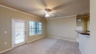This single-story unit in Lafayette, Louisiana offers a thoughtfully designed layout that maximizes functionality. The living area is a standout feature, finished with plush wall-to-wall carpeting, crown molding, and a ceiling fan with integrated lighting. Natural light flows in through a large window and a glass-paneled door that opens to an outdoor balcony, creating a bright and inviting atmosphere.

The kitchen is designed for efficiency, featuring a breakfast bar with dark granite-style countertops, warm wood-toned cabinetry, and black appliances including a refrigerator, stove, and microwave. Wood-style flooring grounds the space, and an adjacent walk-in pantry provides generous storage. Crown molding carries through from the living area, maintaining a cohesive aesthetic.

The bedroom is carpeted and well-lit by a wide window with outdoor views, accompanied by its own ceiling fan. The full bathroom includes a tub-shower combination with tiled surround, wood-style flooring, and built-in open shelving for convenient storage. A dedicated laundry area with a washer hookup and wire shelving adds practical day-to-day convenience to this well-rounded unit.