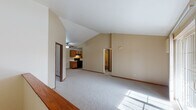 This single-floor unit showcases a thoughtfully designed open layout centered around a spacious living area with striking vaulted ceilings that lend a sense of height and airiness throughout. Neutral-toned carpet flows underfoot, complemented by warm wood baseboards that provide a consistent finish across the main living spaces.

The galley-style kitchen is well-appointed with rich oak cabinetry offering generous storage, white countertops, and black appliances including a range, refrigerator, and dishwasher. A utility area directly off the kitchen conveniently houses in-unit washer and dryer hookups.

The living area opens to a private balcony through a sliding glass door, bringing in natural light and outdoor views. A ceiling fan overhead adds both function and comfort to this main gathering space. A raised half-wall with wood trim defines the transition between the living and entry areas.

The bedrooms feature vaulted or tall ceilings, plush carpeting, and natural light from windows. At least one bedroom includes a walk-in closet with built-in shelving. The full bathroom is finished with tile flooring and includes a tub-shower combination. Throughout the unit, warm beige tones create a cohesive and welcoming ambiance.