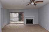 Located at 1350 Greens Pkwy in Houston, TX, this single-story unit offers a well-organized layout designed for comfortable everyday living. The kitchen is a functional highlight, featuring gray cabinetry, granite-style countertops, a stainless steel sink positioned beneath a window, and a full suite of appliances including a black refrigerator, gas range, and stainless steel dishwasher. A skylight overhead adds a welcome touch of natural light to the space, while light wood-style flooring ties the kitchen together. The living area is generously proportioned, featuring neutral carpet flooring, a ceiling fan with light kit, and a white-mantled fireplace that serves as a central focal point. Sliding glass doors open to an outdoor area, allowing natural light to flow freely into the room. Additional carpeted rooms offer flexible use as bedrooms, each equipped with ceiling fans and ample closet space, including walk-in storage. The bathroom is clean and straightforward, with full tub and shower combination set against white tile surround, a toilet, and wood-style flooring. Throughout the unit, a consistent neutral color palette and practical finishes create a cohesive and move-in ready environment.