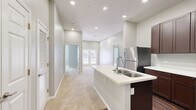 This single-story, 3-bedroom, 2-bathroom home in Conroe, TX offers a thoughtfully designed layout with modern finishes throughout. The kitchen serves as a central highlight, featuring rich dark-brown cabinetry, white countertops, a peninsula island with a double-basin sink, and a full suite of stainless steel appliances including a refrigerator, range, and microwave. Dark hardwood-style flooring anchors the kitchen, creating a sharp contrast with the light-toned walls and counters.

The open hallway connects the kitchen to the living area, which is illuminated by recessed lighting and finished with plush neutral carpeting. French doors at the far end of the living space invite natural light and views of the outdoors. Each of the three bedrooms features soft carpeting, neutral gray walls, and ceiling fans. The bedrooms are generously proportioned, with windows providing natural light, and the secondary bedrooms include closets with paneled doors.

The primary bathroom is well-appointed with dark wood vanity cabinetry, dual sinks, white countertops, and rich hardwood-style flooring, with direct access to a dedicated walk-in closet. The secondary bathroom features a tub/shower combo and a single-sink vanity with matching cabinetry. The home's clean, neutral palette and modern fixtures create a cohesive and move-in-ready atmosphere throughout.