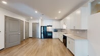 Located at 366 E Broad St in Columbus, Ohio, this single-floor unit offers a thoughtfully designed layout with modern finishes throughout. The kitchen serves as a central highlight, featuring crisp white shaker cabinetry extending to the ceiling, light quartz countertops, a classic subway tile backsplash, and a full suite of black appliances including a gas range, refrigerator, and dishwasher. The open-concept design connects the kitchen seamlessly to a generous living area, where light wood-tone luxury vinyl plank flooring runs throughout the main spaces, complemented by recessed lighting and a clean, neutral color palette. A separate living or flex room benefits from large sliding glass doors that invite natural light and provide views of the surrounding exterior, creating an airy and open atmosphere. The bedrooms offer a comfortable contrast with soft wall-to-wall carpeting, neutral walls, and dark baseboards for a polished finish. The bathroom is well-appointed with wood-tone LVP flooring, a white vanity with an integrated sink, a framed mirror, and a towel bar, maintaining the clean, contemporary aesthetic found throughout the unit. With its modern design, quality finishes, and prime East Broad Street location in downtown Columbus, this space delivers both style and functionality.