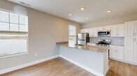 This two-story home in Aurora, Ohio offers a well-designed layout across two floors. The main level features an open-concept kitchen and living area with light hardwood flooring and recessed lighting throughout. The kitchen is appointed with crisp white shaker cabinetry, granite countertops, a subway tile backsplash, stainless steel appliances, and a central island with a built-in sink — ideal for both cooking and casual dining. Large windows fill the living area with natural light and provide views of the surrounding neighborhood.

The entry level also includes a half bathroom with a granite-topped vanity and white cabinetry. Carpeted staircases connect the two floors, which also feature hallways and ample closet storage across four closets. The upper floor houses both bedrooms, including a generously sized primary bedroom with vaulted ceilings, plush carpet, dual windows, and sliding glass doors opening to a private patio with open scenic views. Two full bathrooms on the upper level echo the home's consistent design language with granite vanities and hardwood-style flooring. A dedicated laundry area adds everyday convenience. The home's clean, neutral palette and modern finishes create a bright, move-in-ready atmosphere throughout.
