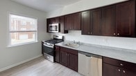 Located at 115 Old Short Hills Road in West Orange, NJ, this well-appointed 2-bedroom, 2-bathroom residence offers a clean, functional layout across a single floor. Gleaming hardwood floors run throughout the living areas and bedrooms, reflecting natural light and adding warmth to the neutral, white-painted walls. The living area is generously sized, featuring multiple windows that frame outdoor greenery and flood the space with daylight, complemented by baseboard heating for year-round comfort. The kitchen is thoughtfully updated with rich dark-espresso cabinetry, light gray countertops, a classic white subway tile backsplash, and a full suite of stainless steel appliances including a gas range, built-in microwave, dishwasher, and refrigerator. Both bedrooms are well-proportioned, each with hardwood flooring, ample natural light from multiple windows, and baseboard heating. The bathrooms are finished in crisp white tile, with one featuring a full tub-shower combination with subway tile surround, a toilet, and a window for ventilation. The overall design is clean and move-in ready, presenting a bright, functional living environment in a residential West Orange setting.